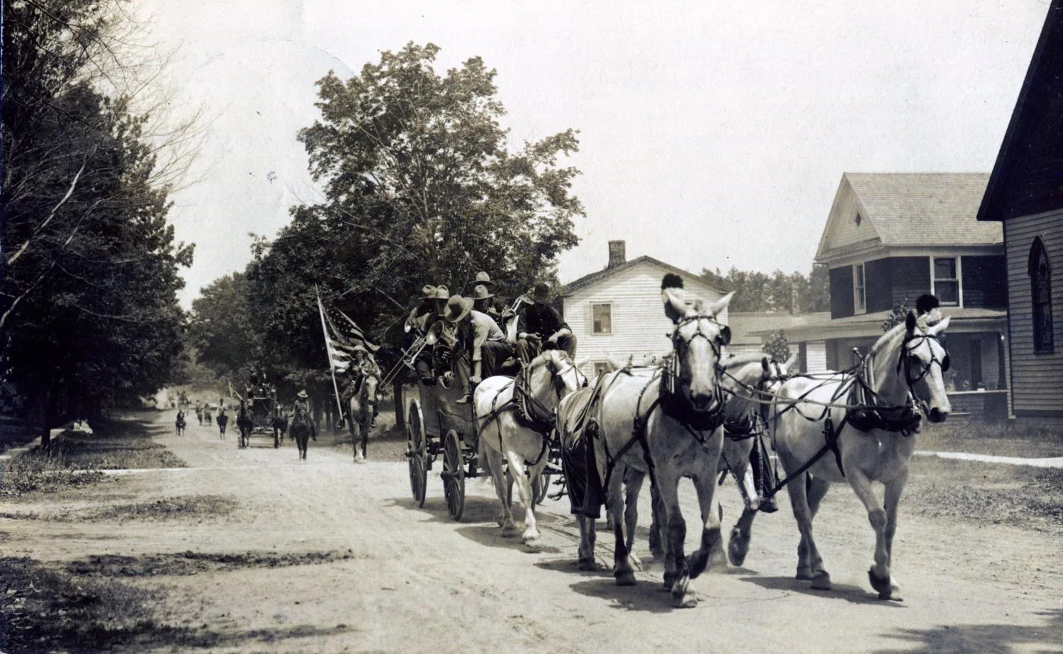 Photograph of a six horse band wagon followed by Mabel Tompkins on Yellow Boy during a parade in Ellisburg, NY, June 30, 1913.