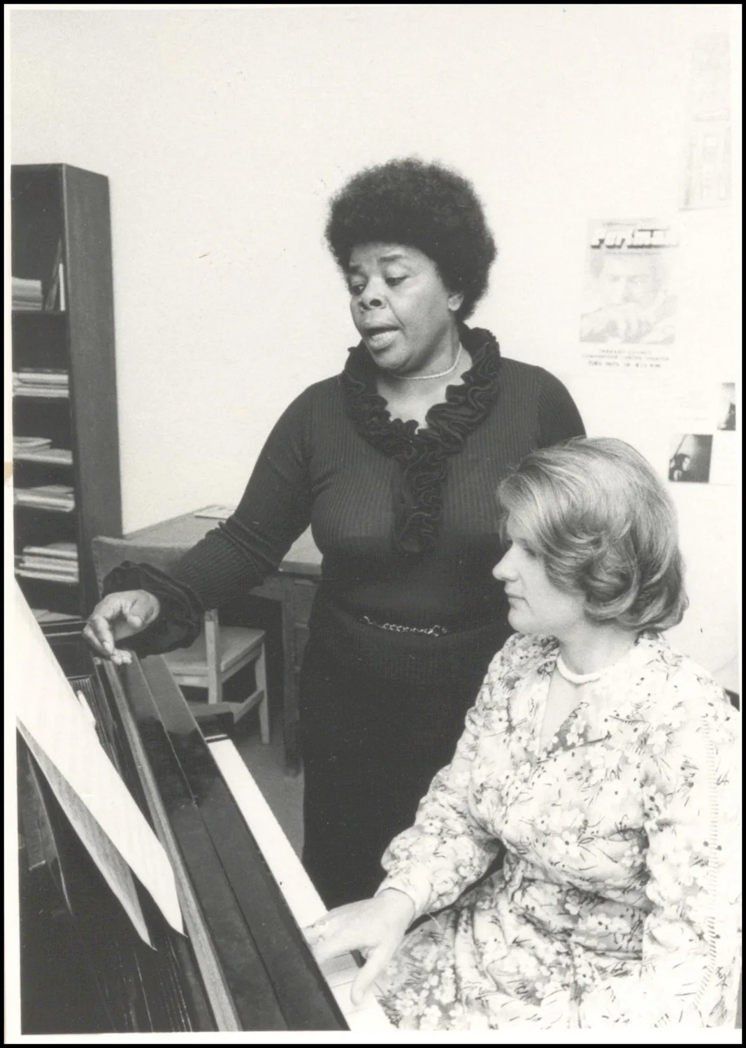 Photograph taken for a story in the Oklahoma Journal newspaper. Caption: "Carol Brice (standing) OU Voice Professor and Deborah Erftenbeck, piano accompanist"