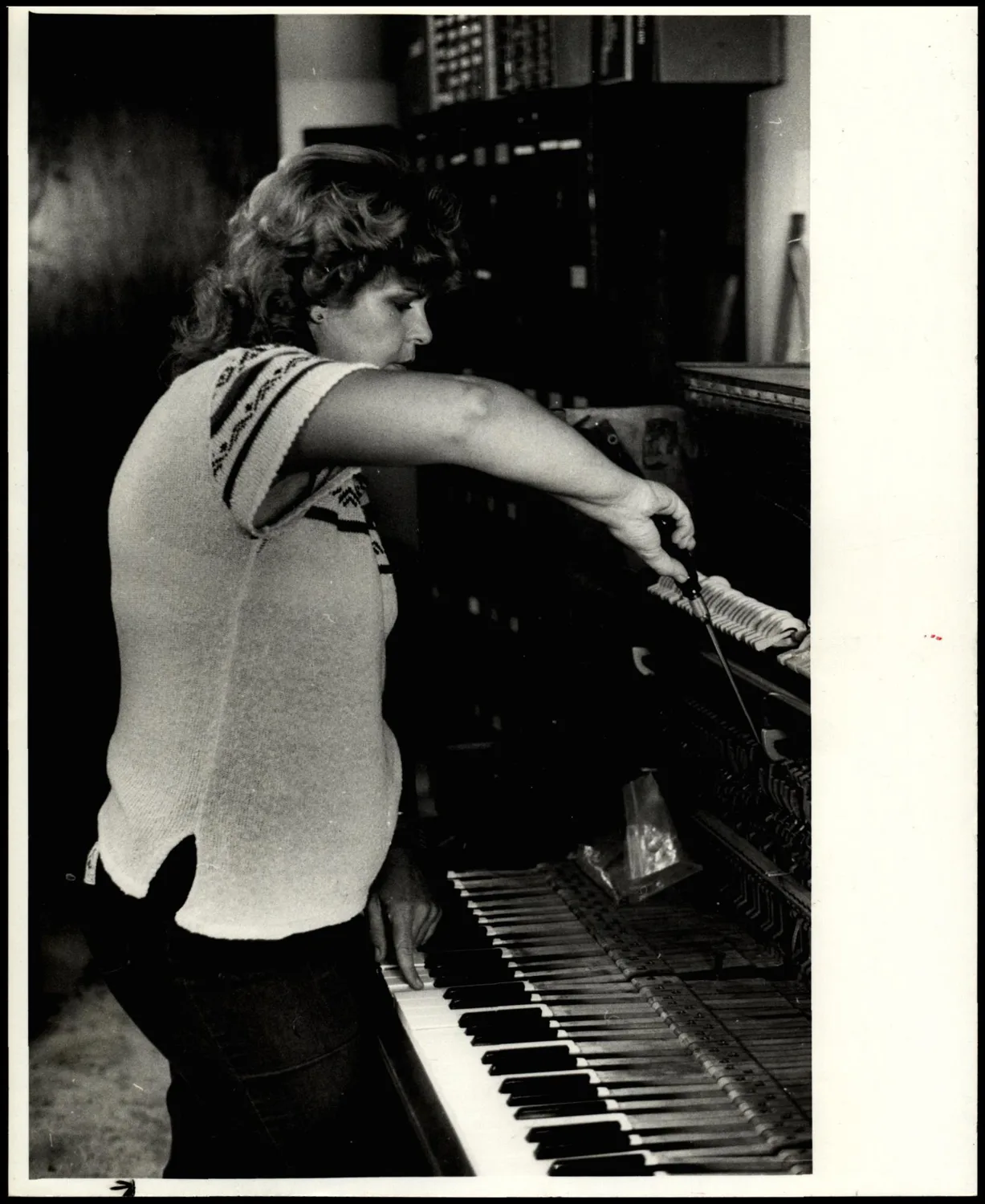 Photograph used for a story in the Daily Oklahoman newspaper. Caption: "Jeannie Jacks fine tunes an upright piano."