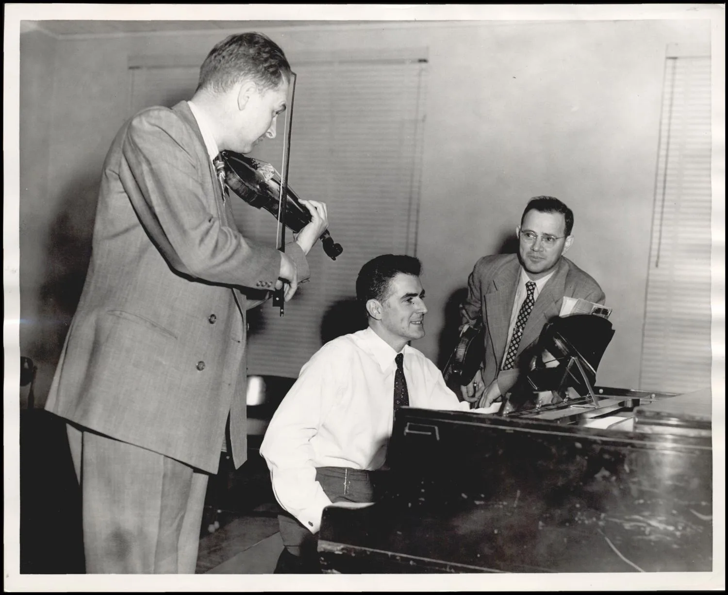 Photograph used for a newspaper owned by the Oklahoma Publishing Company. Caption: "From left, J.M. Brakebill, Alva, concertmaster of the Northwestern Symphony; violin teacher Robert Rudie; and Dr. K.A. Fite, Northwestern State College music dept. head."