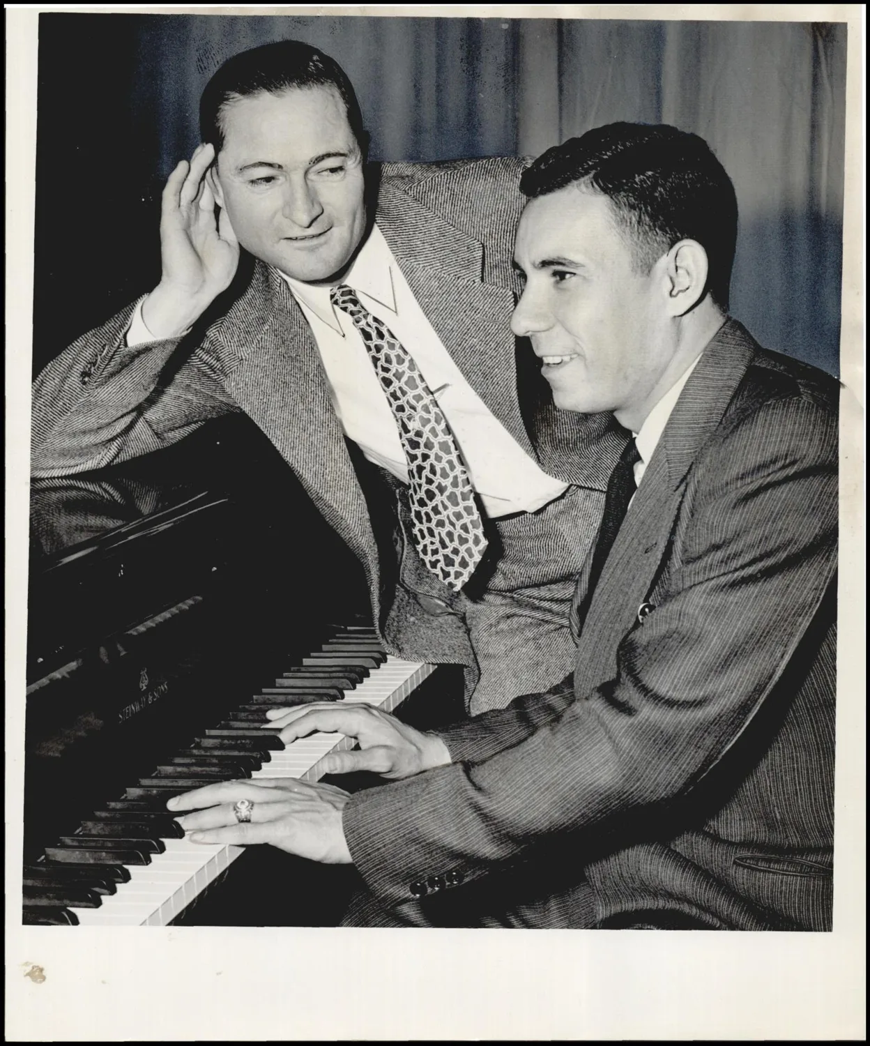 Photograph used for a story in the Oklahoma Times newspaper. Caption: "Sweet music to the ear of Lloyd Waner, Pittsburgh Pirate scout, is the turned out by Tommy Warren, the Tulsa Oilers happy-go-lucky pitcher, who pulled up a backstage piano at the Junior Baseball Jubilee at the Municipal auditorium Friday night."